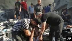 Fələstinlilər İsrailin Qəzza şəhərinə hava hücumu nəticəsində bir evin dağıntıları altında qohumlarını itirdiyinə görə ağlayan kişini təsəlli edirlər. 4 noyabr, 2023. 