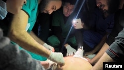 Medical services use phone flashlights to assist a Palestinian wounded in Israeli strikes at the Indonesian hospital after Al Shifa hospital has gone out of service amid Israeli ground offensive, in the northern Gaza Strip, Nov. 16, 2023.