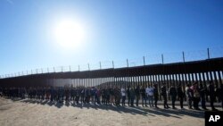 FILE - People line up to receive food from volunteers with Border Kindness after crossing the border with Mexico, near Jacumba, California, Oct. 24, 2023.