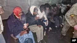 In this photo released by Governor of Murmansk region Andrey Chibis on Nov. 22, 2023, migrants gather getting hot drinks inside a tent near Russia's border with Finland.