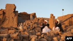 Afghan residents sit at a damaged house after earthquake in Sarbuland village near Zinda Jan, a district in the central part of the Afghan province of Herat, Oct. 7, 2023.