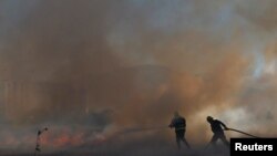 Maafisa wa zimamoto wa Afrika Kusini wakiwa katika harakati za kuuzima moto kwenye msitu wa karibu na Hanover Park, Cape Flats, mjini Cape Town, Afrika Kusini, Machi 11, 2024.