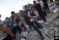 A Palestinian takes a child out of the rubble after Israeli airstrikes in Khan Younis, Gaza Strip, Oct. 16, 2023.
