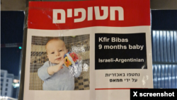 ایک پوسٹر پر حماس کی قید میں سب سے کم عمر مغوی کفیربیباس کی تصویر۔ فائل فوٹو