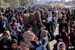 Palestinians carry some belongings as they flee Khan Younis to safer areas, Jan. 26, 2024.