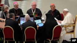 Pope Francis, right, speaks with a group of voting members during the opening session of the 16th General Assembly of the Synod of Bishops in the Paul VI Hall at the Vatican, Oct. 4, 2023