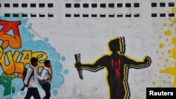 রংপুরে নিহত আবু সাইদের গ্রাফিতি আঁকা দেয়ালের পাশ দিয়ে ঢাকায় দুজন শিক্ষার্থী হেঁটে যাচ্ছে। ফটোঃ ১১ অগাস্ট, ২০২৪।