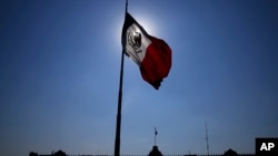FILE - A Mexican flag waves in front of The National Palace, the office of the president, in Mexico City's main square, the Zocalo, at sunrise, April 24, 2023. 