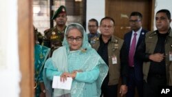Bangladesh Prime Minister Sheikh Hasina checks her watch as she waits outside a polling station for the official opening time to cast her vote in Dhaka, Bangladesh, Jan. 7, 2024.