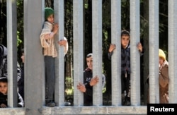 FILE - Migrants stand near the wall on Polish Belarusian border near Bialowieza, Poland, May 28, 2023.