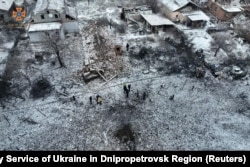 Warga berdiri di samping rumah tempat tinggal yang hancur di lokasi serangan rudal Rusia di Wilayah Dnipropetrovsk, Ukraina, 8 Januari 2024. (Foto: via Reuters)