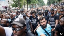 Assa Traore, center, raises her fist during a banned protest against police violence, July 8, 2023 in Paris. Her brother Adama died in the custody of French police in 2016.