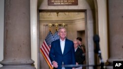 Speaker of the House Kevin McCarthy, joined at right by his top negotiator on the debt limit, Rep. Patrick McHenry, smiles as he arrives to talk to reporters at the Capitol in Washington, May 28, 2023. 
