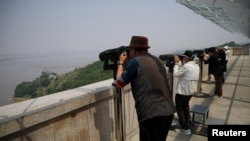 FILE - South Korean people look toward the North through binoculars at an observation post near the demilitarised zone separating two Koreas in Paju, South Korea, May 17, 2022. 