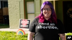 Leah Dean, a native of the Texas Panhandle, poses outside her home, July 3, 2023, in Denver. In Texas, Dean had been scared to fly an abortion rights banner outside her house.