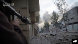 FILE - In this image from video released by Hamas on Dec. 2, 2023, a Hamas fighter aims an Al-Yasin rocket at an Israeli armored vehicle in Beit Hanoun, Gaza.