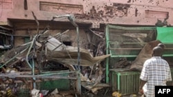 Warga mengamati gedung pusat medis yang penuh lubang peluru di Souk Sitta (Pasar Enam) di selatan Khartoum, 1 Juni 2023. (AFP)