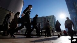FILE - Commuters walk in a passageway during a rush hour at Shinagawa Station in Tokyo, Feb. 14, 2024. 