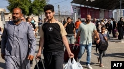 Orang-orang berjalan melalui gerbang perbatasan Rafah di Jalur Gaza selatan untuk memasuki Mesir setelah dibukanya perbatasan Rafah hari Rabu, 1 November 2023.