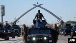 Iraqi Army soldiers drive their armored vehicles under the Victory Arch during a parade marking the Army Day in Baghdad, Jan. 6, 2024.