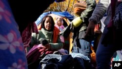 Migrant women from Venezuela look over new clothes, Wednesday, Nov. 1, 2023, outside a Northside police station where they live in a small tent community in Chicago. (AP Photo/Charles Rex Arbogast)