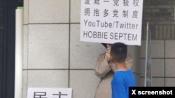 2023年6月22日，网传北京大学一食堂门外有年轻人举牌呼唤民主革命和多党制取代一党极权。（推特图片）