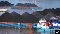 Kapal berlayar di dekat tongkang yang terisi penuh batu bara di sungai Mahakam di Samarinda, Kalimantan Timur, 19 Desember 2022. (AP/Dita Alangkara)