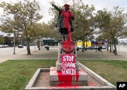 FILE - In this Oct. 14, 2019, file photo, a sign reading "stop celebrating genocide" sits at the base of a statue of Christopher Columbus in Providence, R.I., after it was vandalized with red paint. (AP Photo/Michelle R. Smith, File)