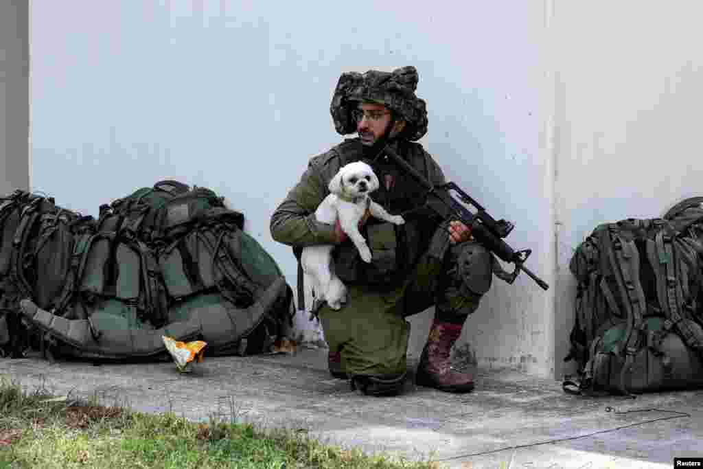 An Israeli soldier holds a rescued dog as he takes position near a bomb shelter in Kibbutz Kfar Aza, in southern Israel. REUTERS/Ronen Zvulun&nbsp;