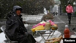 រូបឯកសារ៖ អាជីវករ​លក់​បន្លែ​នៅ​ពេល​មាន​ព្រិល​ធ្លាក់​ក្នុង​ក្រុង Omsk នៃ​ប្រទេស​រុស្ស៊ី កាលពី​ថ្ងៃទី២៤ ខែតុលា ឆ្នាំ២០២៣។