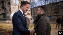 乌克兰总统泽连斯基和荷兰首相马克·吕特2024年3月1日在哈尔科夫被俄罗斯导弹袭击损坏的住宅楼附近交谈。