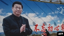 资料照：一名男子骑着电动车路过北京街头的一幅宣传画。（2023年2月28日）