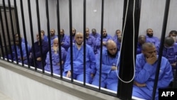 Para tersangka militan kelompok Negara Islam (IS) duduk di bilik terdakwa selama persidangan di kota Misrata, Libya barat laut pada 29 Mei 2023. 