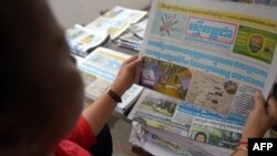 ស្ត្រី​ម្នាក់​អានទំព័រ​មុខនៃ​កាសែត​រស្មី​កម្ពុជាកាលពីថ្ងៃទី​១៥ វិច្ឆិកា ឆ្នាំ២០១៥។(Photo by TANG CHHIN SOTHY / AFP)