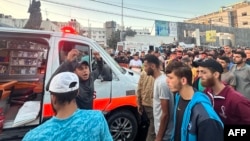 People gather around an ambulance damaged in a reported Israeli strike in front of Al-Shifa hospital in Gaza City on Nov. 3, 2023.