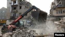 یک امدادگر در کنار ساختمان‌های مسکونی آسیب دیده در حمله روسیه به شهر سلیدوفه، در منطقه دونتسک