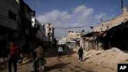 Warga Palestina berjalan di jalan rusak pasca operasi tentara Israel di kamp pengungsi Jenin, Tepi Barat, Minggu, 26 November 2023. (Foto: AP)