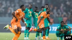 Basani ba Côte d'Ivoire #20 Christian Kouame (G) na #17 Serge Aurier (D) bazali kosepaela nsima na kopolisa Senegal na 8e ya CAN, na stade Charles Konan Banny na Yamoussoukro, Côte d'Ivoire, 29 sanza ya yambo 2024. 