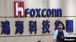 资料照：一名女子走过台北鸿海科技集团大楼外的富士康标识。（2922年11月9日）