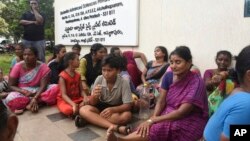 Relatives of the victims killed in a fire triggered by an explosion at the Escientia Advanced Sciences Private Ltd., a pharmaceutical company, sit outside the factory, in Atchutapuram, Andhra Pradesh state, India, Aug. 22, 2024. 