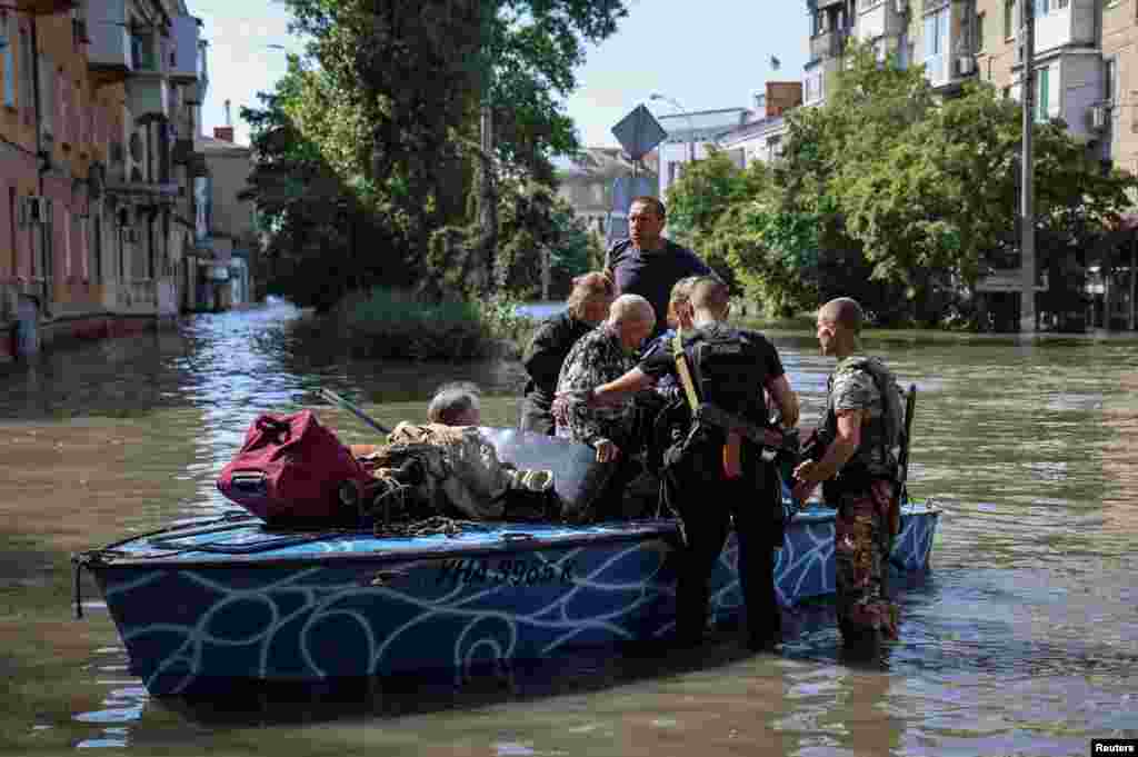 Police evacuate local residents from a flooded area after the Nova Kakhovka dam breached, in Kherson, Ukraine, June 7, 2023.