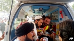 Seorang petugas SAR membawa seorang pria yang cedera masuk ke ambulans setelah ledakan bom di distrik Bajur, Khyber Pakhtunkhwa, Pakistan, Minggu, 30 Juli 2023. (Foto: Rescue 1122 via AP)
