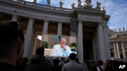 Pope Francis is seen coughing on a giant screen during the Angelus noon prayer, from the chapel of the hotel on Vatican grounds where he lives, Nov. 26, 2023.