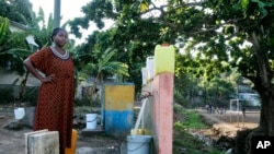 A woman waits for her bucket to be full at a water point in M'tsamoudou, near Bandrele, on the French Indian Ocean territory of Mayotte, Oct. 21, 2023. Water taps flow just one day out of three because of a drawn-out drought compounded by years of water mismanagement.