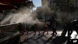 People walk along the Las Vegas Strip in the heat, July 13, 2023, in Las Vegas.