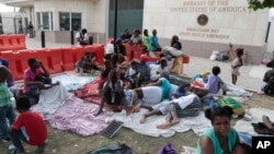 People displaced by armed gangs from their homes in the Tabare neighborhood rest outside the U.S. Embassy in Port-au-Prince, Haiti, July 25, 2023.