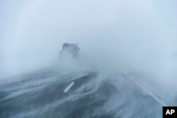 A truck moves along the snow-blown eastbound lane of US Highway 20 during a blizzard near Sac City, Iowa, Jan. 13, 2024.
