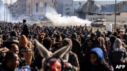 یک تانک اسراییل در عقب فلسطینی‌هایی که منطقه از خان یونس در جنوب نوار غزه در حال فرار استند 