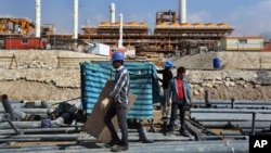 FILE - Construction workers move materials at a gas refinery in Asalouyeh, Iran, on Jan. 22, 2014. The Iranian parliament voted on Nov. 19, 2023, to raise the retirement age for men from 60 to 62.