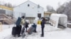 FILE - A family crosses into Canada at Roxham Road, an unofficial crossing point from New York state to Quebec for asylum-seekers, in Champlain, N.Y., March 25, 2023. 